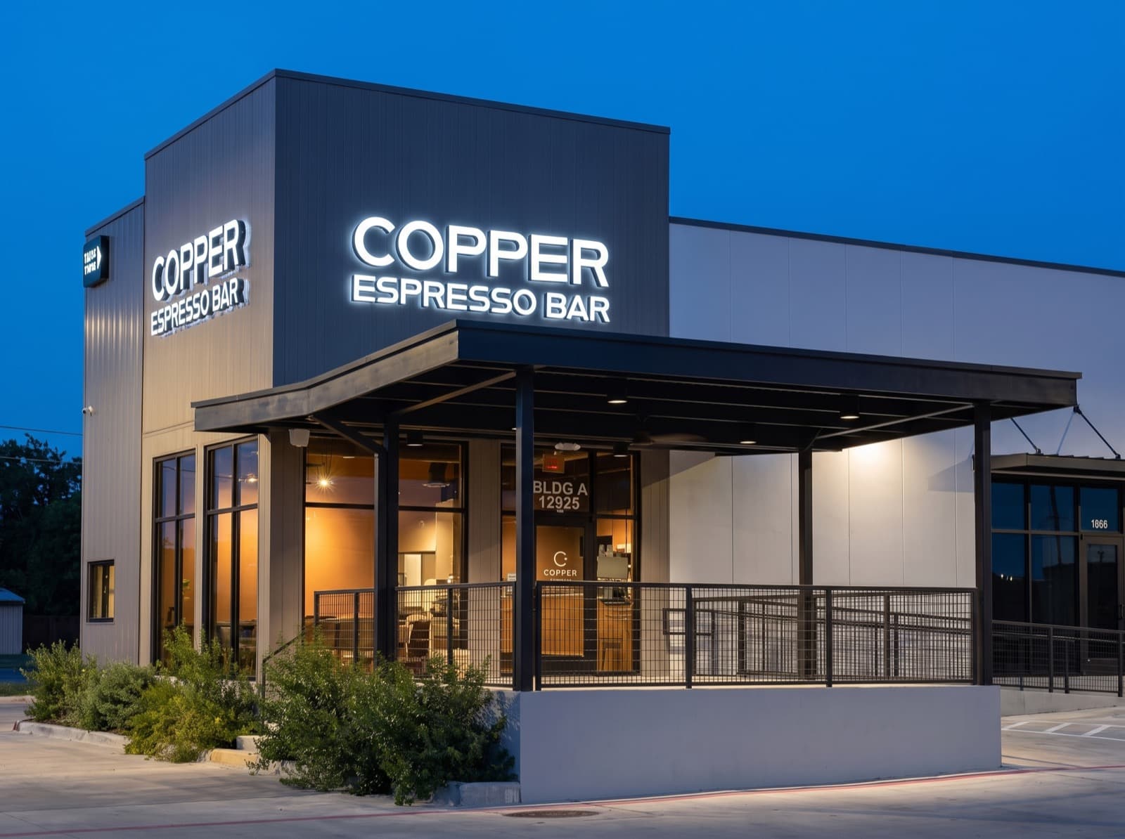 Backlit exterior sign above a storefront at dusk